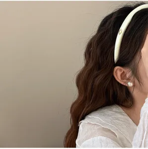 Vue détaillée d'un serre-tête en satin rembourré avec un emblème doré sur les cheveux.