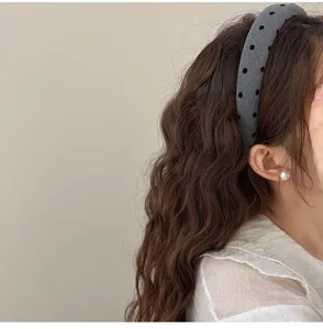 Vue latérale détaillée d'un serre-tête rembourré gris à pois sur de longs cheveux bouclés