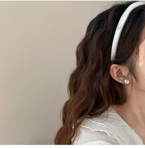 Détail rapproché d'un serre-tête rembourré en satin blanc avec un logo doré chic.