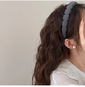 Vue détaillée d'un serre-tête rembourré gris avec motif coeur noir porté par un modèle