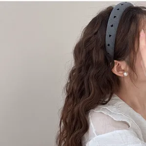 Détail d'un serre-tête en tissu gris avec des motifs de cœur sur cheveux bouclés