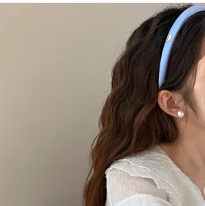 Détail d'un serre-tête en satin bleu clair avec une plaque dorée ovale élégante