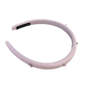 Diadema acolchada rosa con pedrería brillante para un peinado con mucho volumen.
