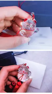 Macro detail of a faceted crystal lucky cat car pendant with red tassels and gold beads