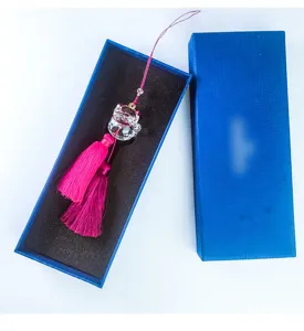 Detailed macro shot of crystal lucky cat car ornament with pink tassels in a blue box.