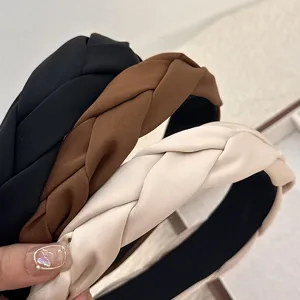 Serre-tête élégant en satin tressé aux tons neutres pour une coiffure à volume élevé.