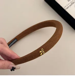 Primer plano de diadema de esponja marrón con lazo dorado y textura de canalé suave