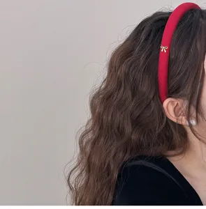 Primer plano lateral de una diadema acolchada roja con un pequeño lazo dorado elegante.