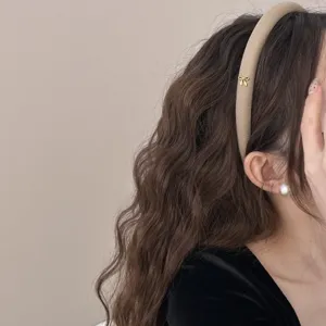 Diadema de esponja beige elegante con detalle de mariposa dorada en pelo castaño