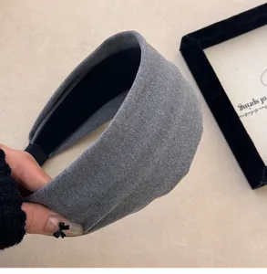 Gros plan détaillé d'un bandeau large en tricot gris montrant la texture douce