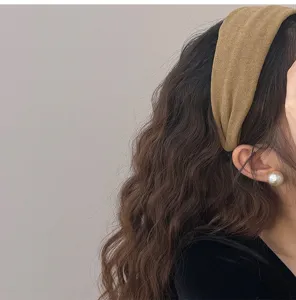 Vue détaillée d'un bandeau large en velours jaune moutarde sur cheveux ondulés