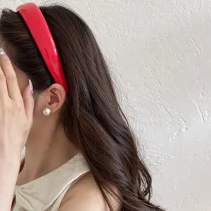 Side view detail of a vibrant red padded leather headband styled with elegant pearl earrings