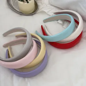 Multi-colored padded leather headbands arranged on white cloth for high cranial top effect.