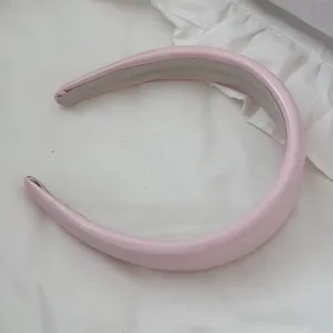 Detail view of a light pink padded leather headband with high-top sponge design.