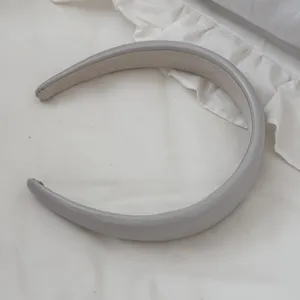 Detailed macro view of a grey padded leather headband resting on soft white fabric