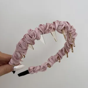 Close-up detail showing the pink satin pleated texture and plastic teeth of the headband.
