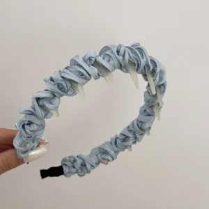 Close-up of light blue satin ruffled headband with clear non-slip plastic teeth.