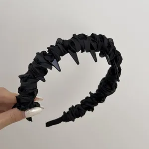 Close-up of black ruffled satin headband featuring inner anti-slip teeth for secure fit.