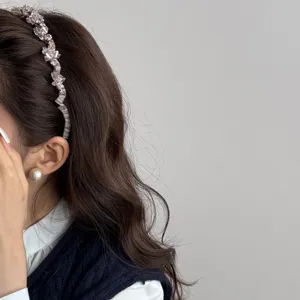 Elegant minimalist crystal rhinestone headband and pearl earring on a stylish model.