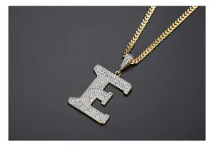 Detalle del colgante letra E con circonitas micro-pave en cadena cubana dorada de lujo