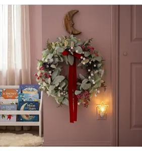Festive Christmas wreath with red velvet ribbon and lamb's ear leaves on pink wall