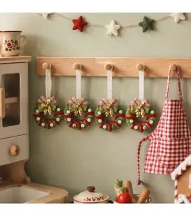 Set of mini festive Christmas wreaths hanging on a wooden wall rack in a kitchen