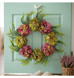 Close-up of a floral wreath with purple hydrangeas and green ferns on a mint door