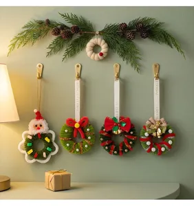 A detailed view of four assorted mini Christmas wreaths hanging on golden wall hooks