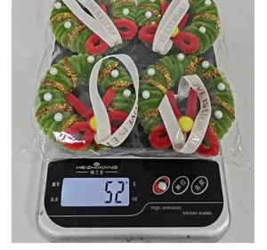 Set of four mini Christmas wreath ornaments being weighed on a digital kitchen scale