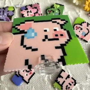 Close-up of a pink pixel art pig fuse bead creation on a clear acrylic display stand