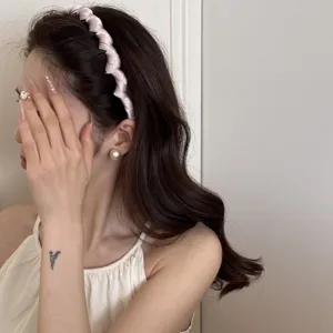 Side view of a pink satin wavy headband showing the high skull top effect on an Asian model