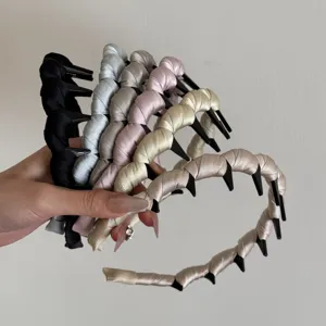 Hand holding a set of satin thickened wave headbands with comb teeth in various colors
