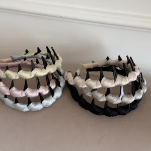 Collection of satin padded headbands with wave-shaped comb inserts in pastel colors.