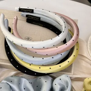 Vue détaillée de serre-têtes en satin coloré avec d'élégants motifs à pois noirs