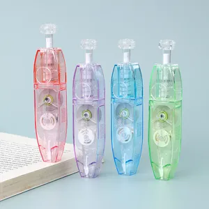 Cintas correctoras estilo bolígrafo translúcidas en cuatro colores junto a un libro