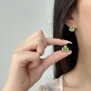 Detalle de elegantes pendientes de tulipán en oro con ojo de gato verde y diamantes