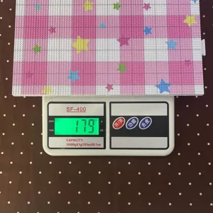 Macro view of 2.6mm pink checkered fuse bead board weighing 179g on digital scale