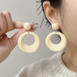 Close-up view of retro French style geometric cream round earrings on ear and hand