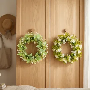 Artificial white floral and green leaf wreaths hung on wooden doors for home decor