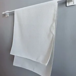 Large white textured bath towel hanging on a minimalist white rack