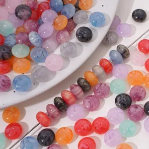 Vue détaillée de perles en résine marbrée colorée enfilées sur une aiguille en argent