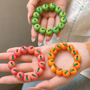 Detalle de pulseras de frutas de resina hechas a mano en verde, rosa y naranja