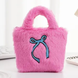 Detailopname van de zachte roze pluche handtas met een blauw geborduurd strikje.