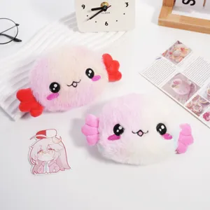 Dettaglio di simpatici portamonete in peluche a forma di axolotl con volti ricamati su una scrivania.