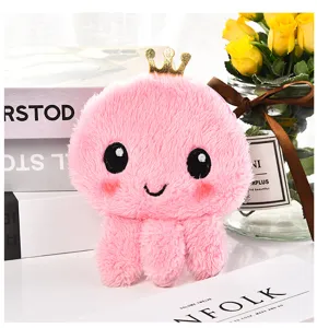 Close-up of pink plush octopus coin purse with gold crown on books lifestyle view