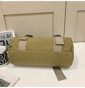 Side view of a mustard yellow grid cylinder sports bag with adjustable straps