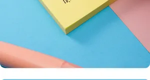 Nahaufnahme eines rosa Korrekturbands auf blauem und gelbem strukturiertem Papier