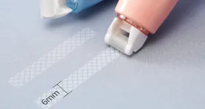 Makroaufnahme von 6mm Punktkleber-Applikator Klebestreifen auf Papieroberfläche