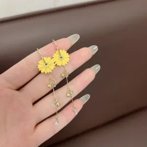 Detail of French style yellow daisy earrings with elegant gold tassels and crystal beads