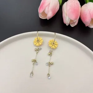 Close-up of French pastoral yellow daisy asymmetrical tassel earrings on white plate